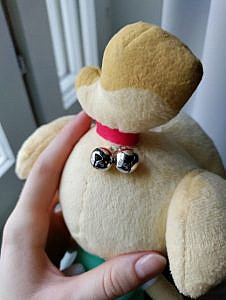 The backside of the Isabelle plushie's head. The plushie has a red ribbon and two bells attached to its head.