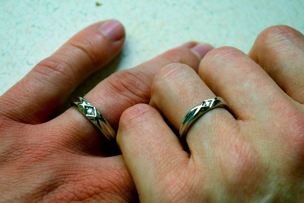 Two interlocked hands with wedding rings