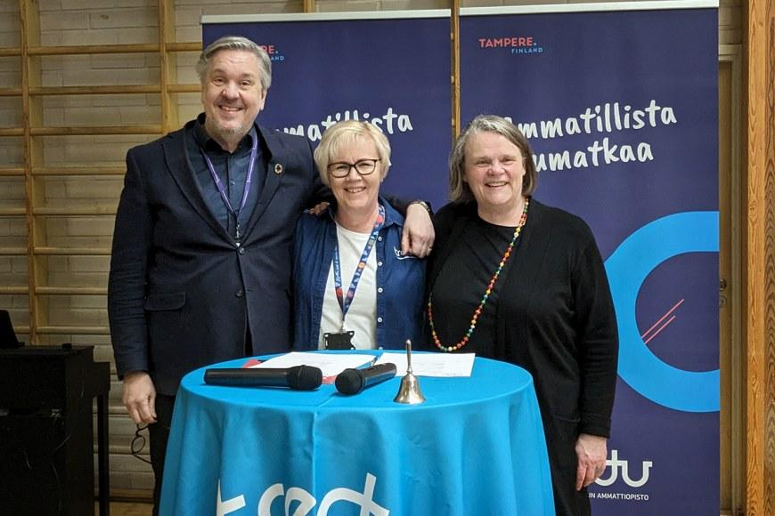Juha Lahtinen, Kirsi Viskari ja Hanna Ilola Tredun pääkampuksen salissa allekirjoituspisteellä.