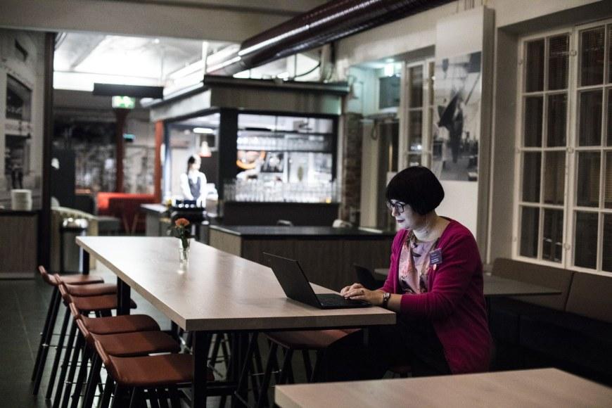 Nainen käyttää tietokonetta kahvilassa.