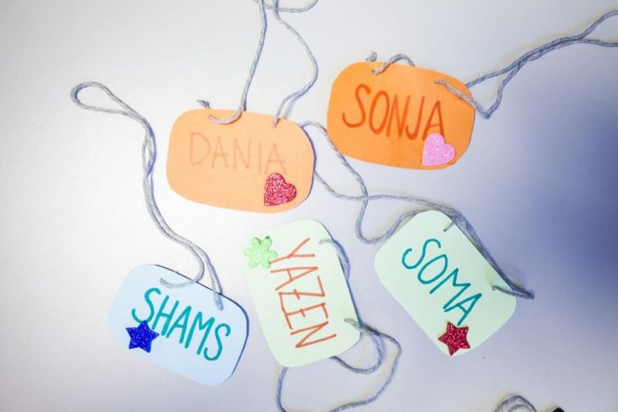 Viisi itsetehtyä nimikylttiä, joissa nimet Dania, Sonja, Shams, Soma ja Yazen.