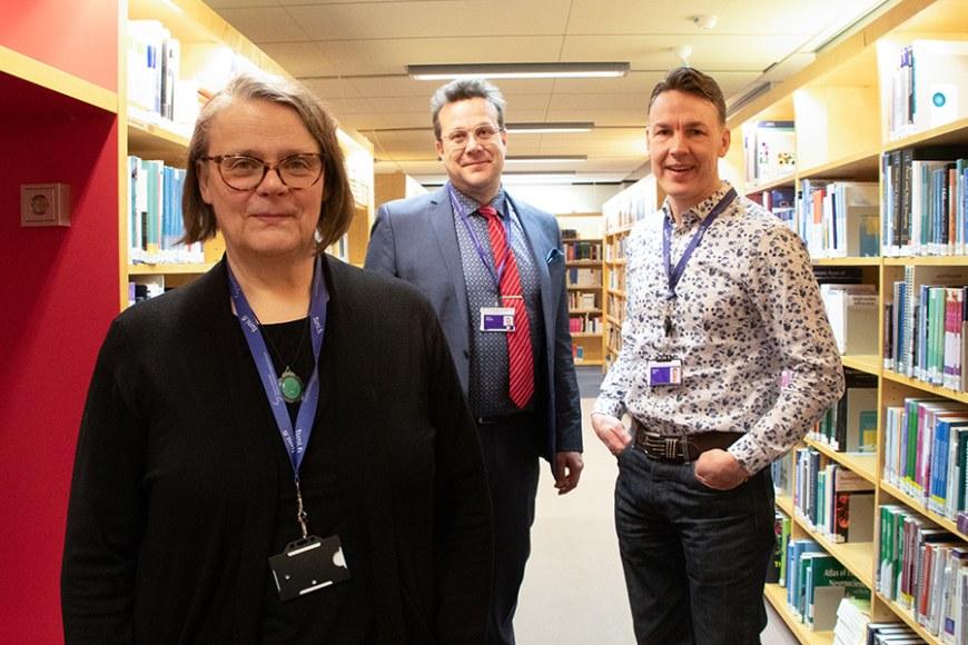 Hanna Ilola, Markus Aho ja Hannu Koponen TAMKin kirjaston hyllyjen välissä.