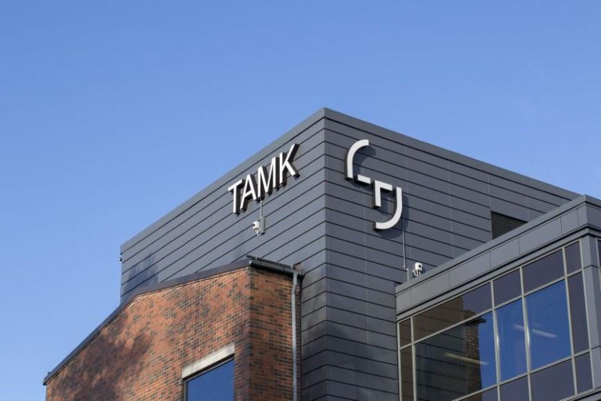 Rakennus, jonka seinässä TAMKin logo. Taustalla sininen taivas. 