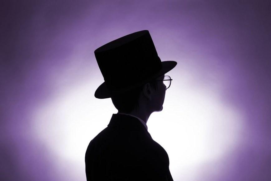 A human figure wearing a doctor's hat, with a black silhouette against a purple background.