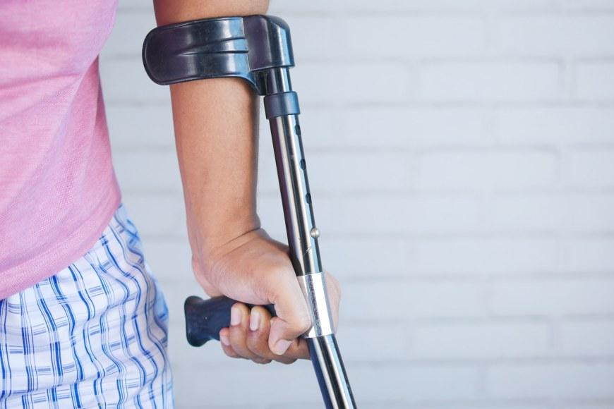 A person with injured arm and crutch.