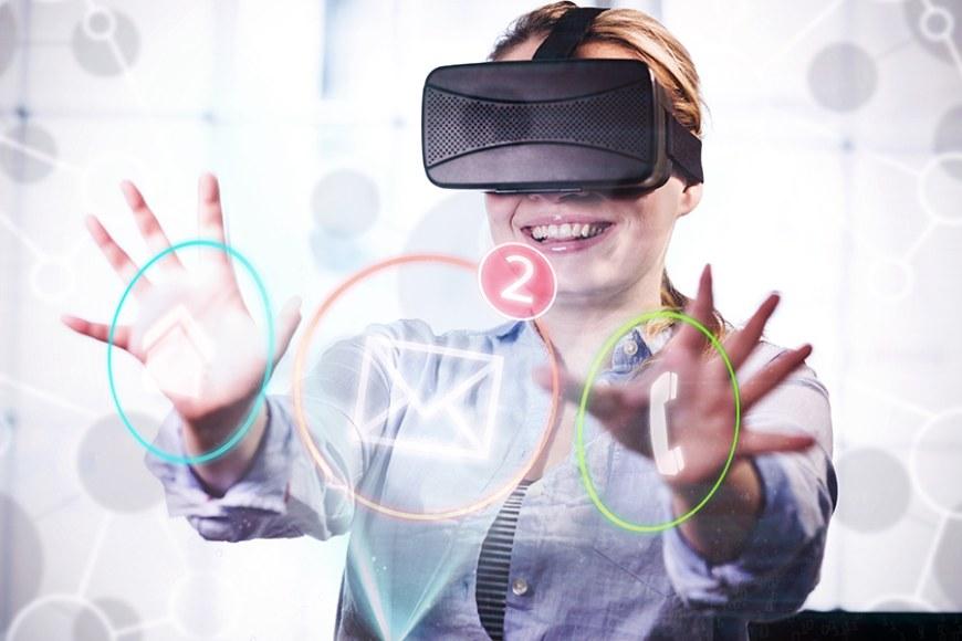 Hymyilevä nainen VR-lasit päässä koskettaa virtuaalisia painikkeita. 