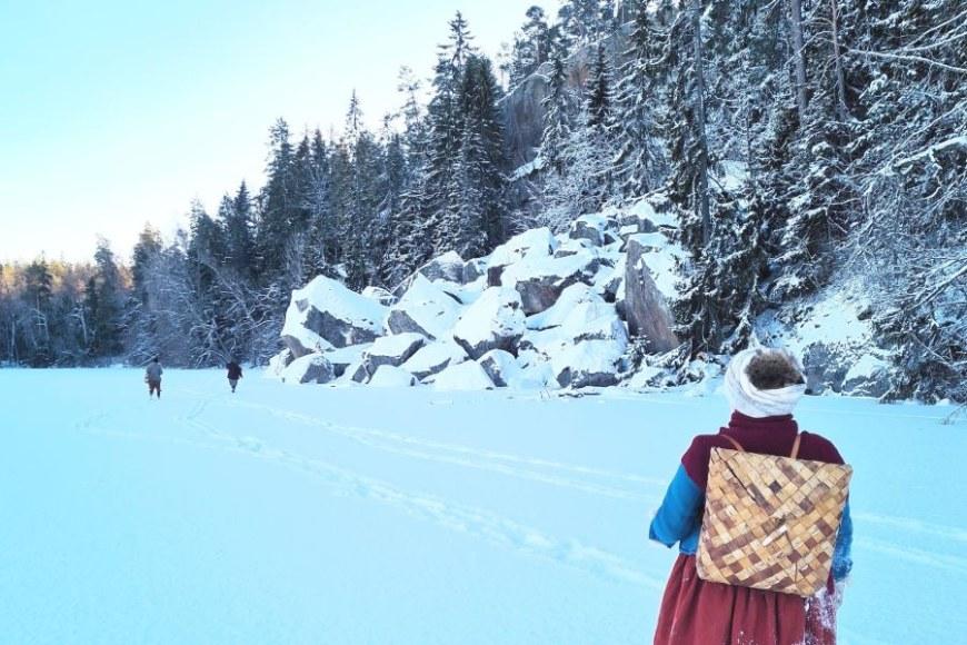 1600-luvun maalaisnaiseksi pukeutunut elävöittäjä seisoo järven jäällä selkä katsojaan päin. Hän on jatkamassa taivaltaan jään poikki selässään tuohikontti. Järven rannalla näkyy lumen ja jään peittämiä kallioita ja metsää. 