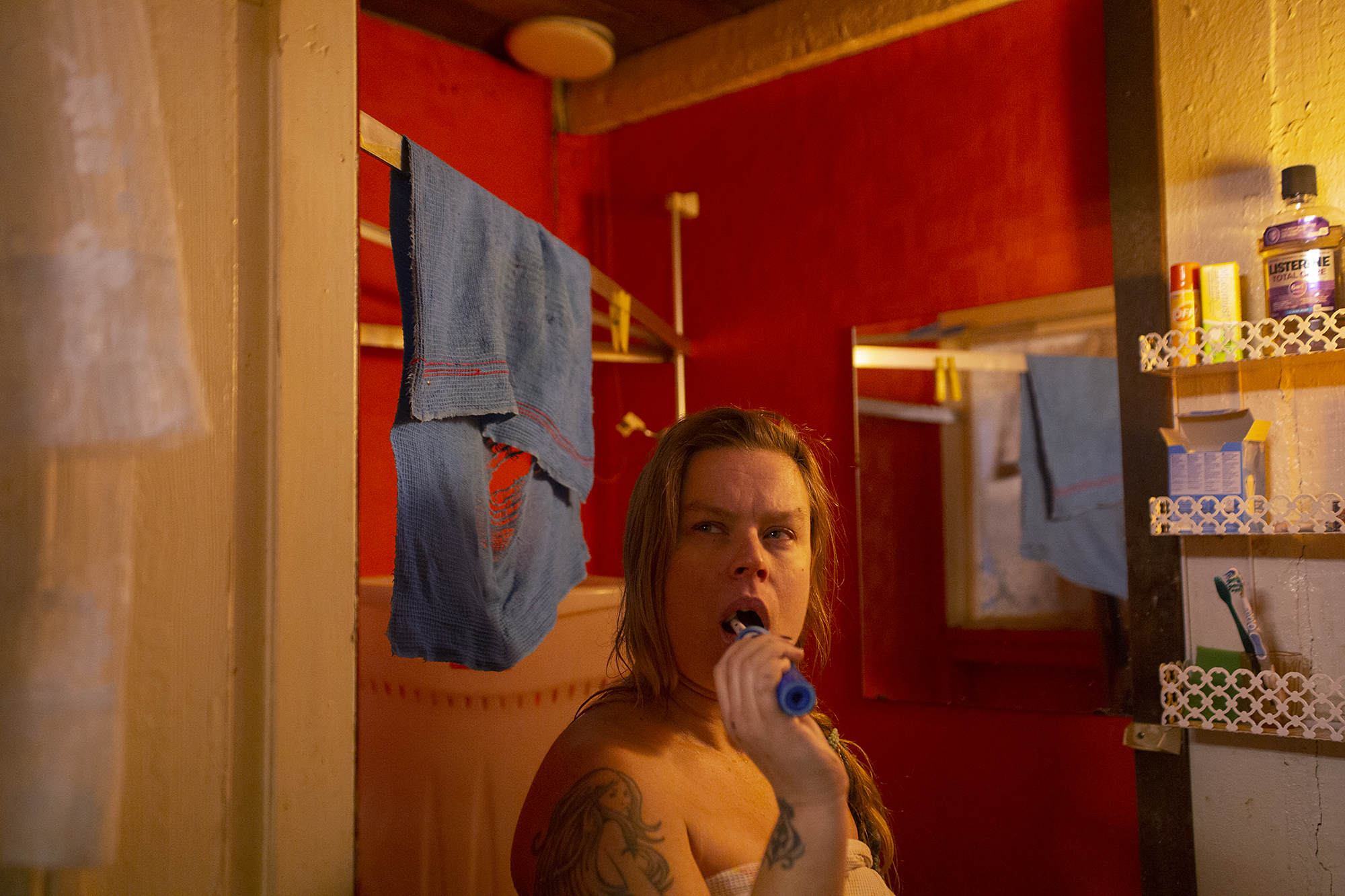 Nainen pesee hampaita punaisessa vessassa