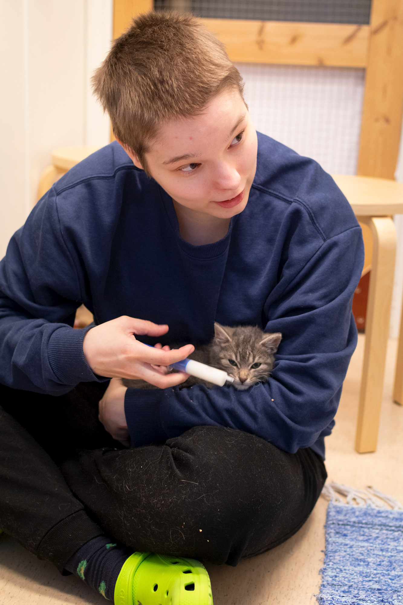 Nainen istuu lattialla kissa sylissään.