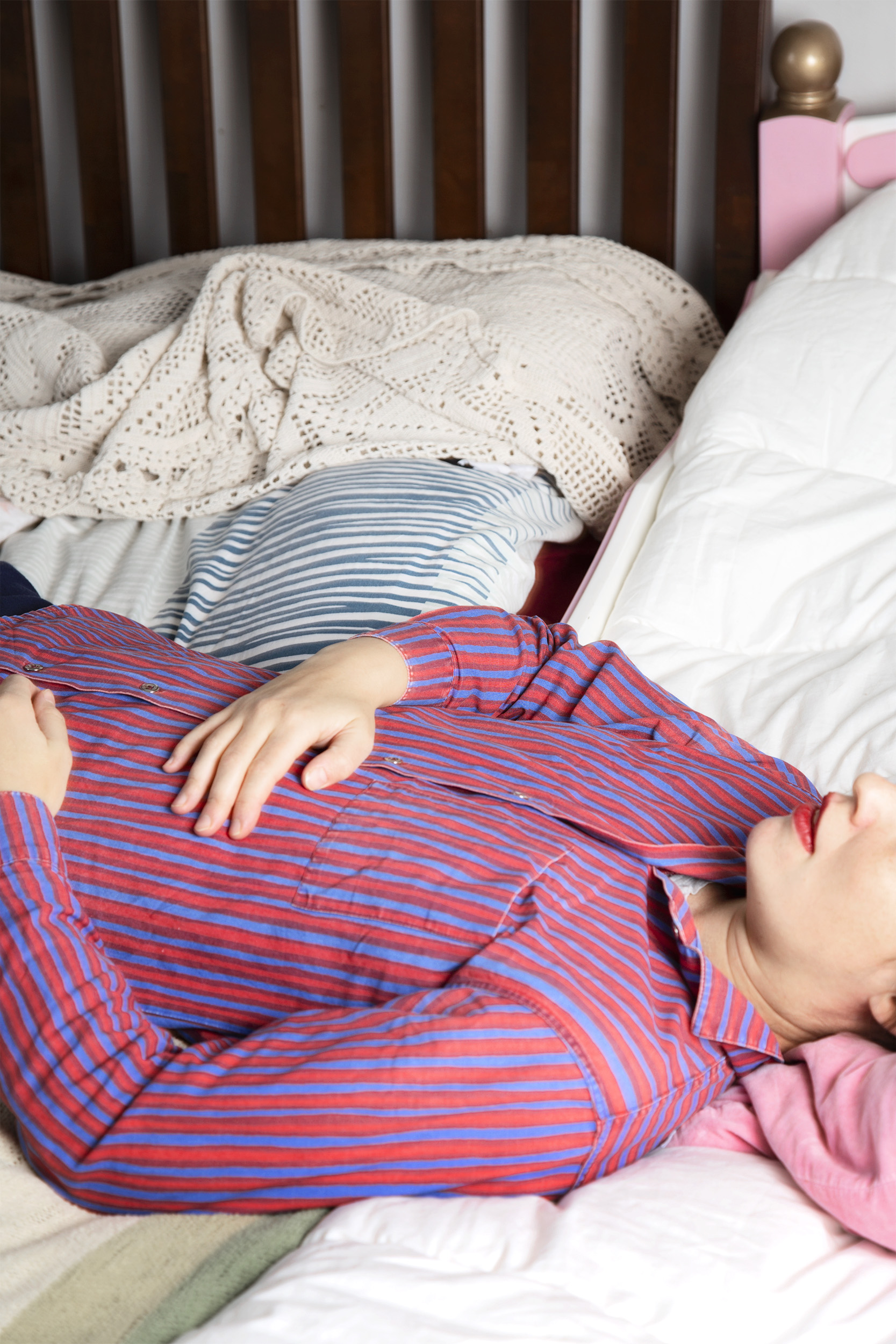 Kuva, jossa nainen makaa sängyllä niin, että silmät on rajattu kuvan ulkopuolelle.