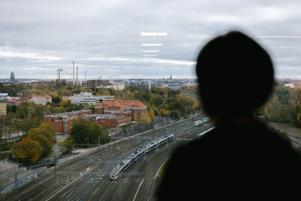 Pia Salmi katsoo ulos toimiston ikkunasta, josta näkyy junarata ja maisema kohti Helsingin keskustaa.
