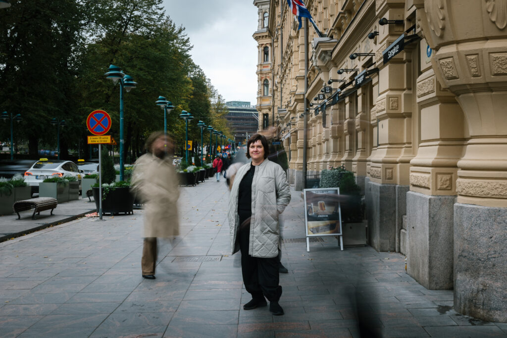 Pia Salmi seisoo Esplanadin kävelykadulla. Ympärillä kävelee kaupunkilaisia.