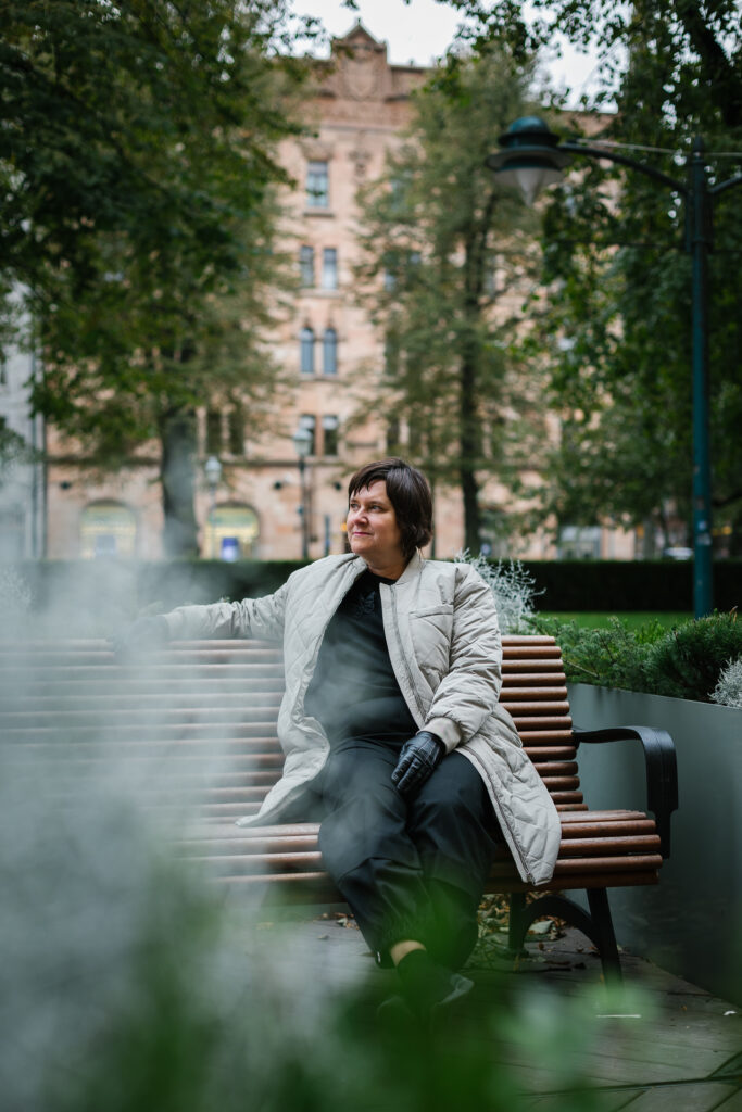 Pia Salmi istuu penkillä Esplanadin kävelykadulla. Taustalla näkyy vanhoja rakennuksia.