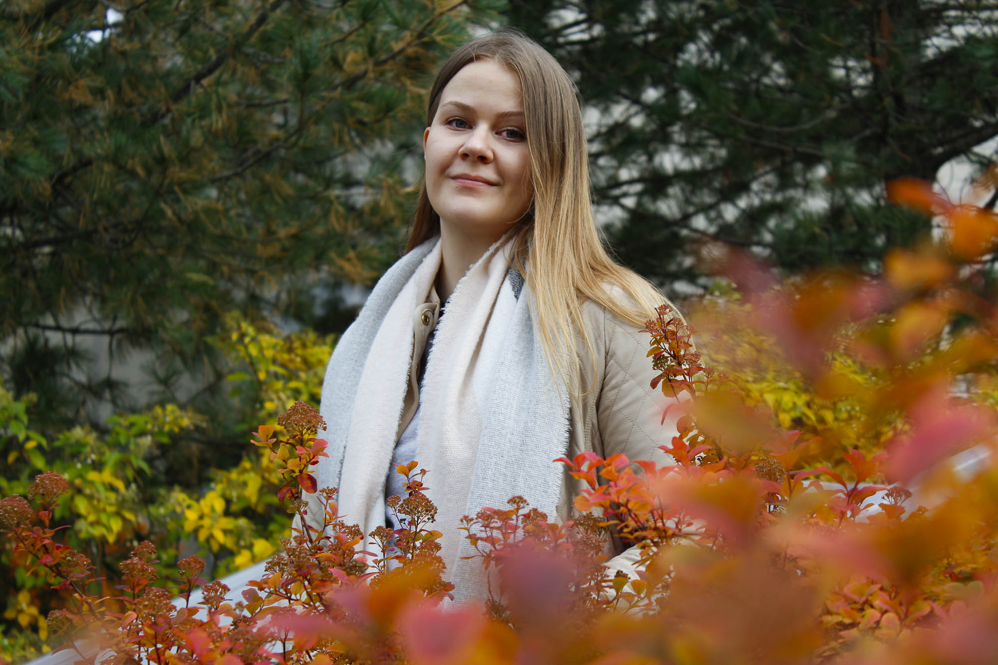 Kuvassa Maija Luukko poseeraamassa hymyillen ruskan värien ympäröimänä.