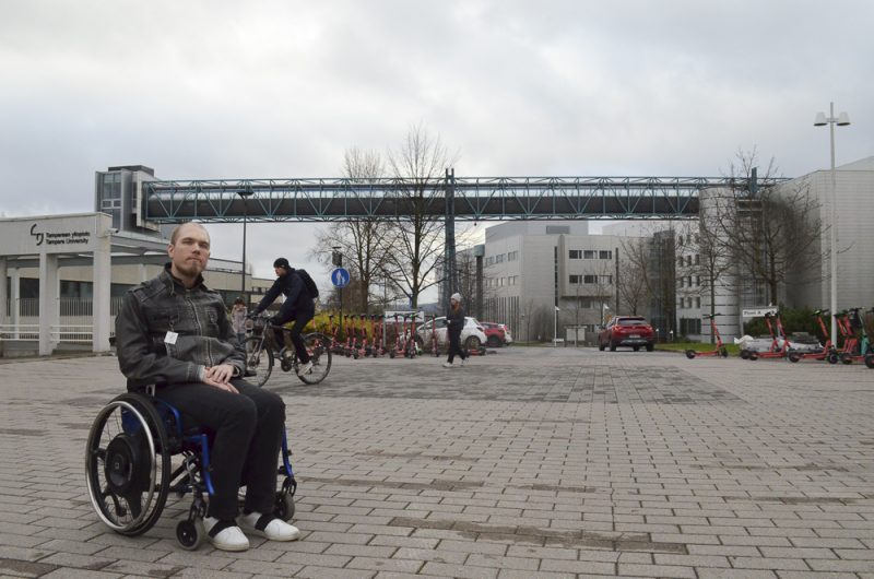 Henry Kvist liikkuu pyörätuolilla Tampereen yliopiston keskustakampuksen pihalla.