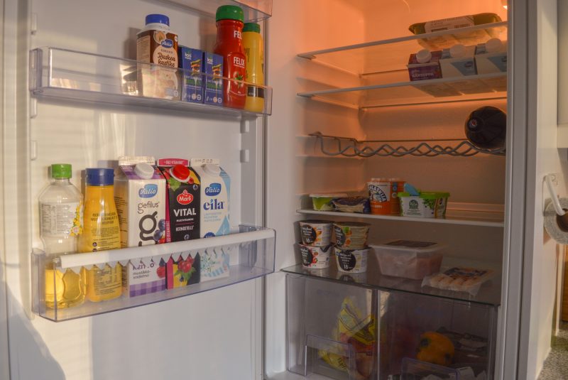 Kuvassa on auki oleva jääkaappi. Jääkaapissa on muun muassa maitoa, perunoita ja kanasuikaleita.