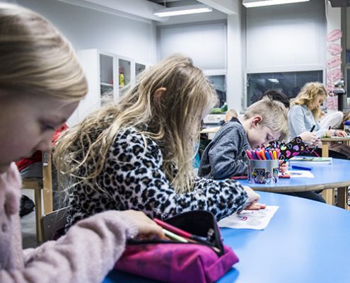 Viisi alakoulun oppilasta ovat oppitunnilla värittämässä monisteen tehtävää.