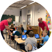 Kuvassa opettajat Tuomo ja Mikko ovat opastamassa oppilaita iPadien käyttöönotossa.