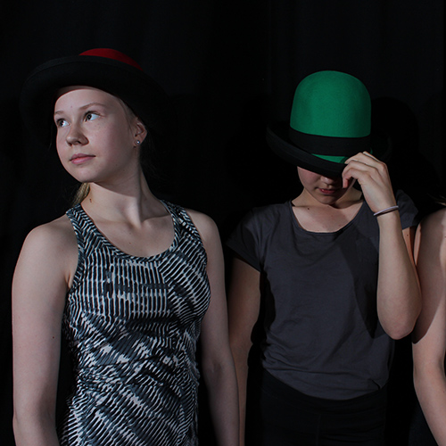 Sirkus-kuvassa on läheltä kuvattuna kaksi oppilasta, toisella punainen ja toisella vihreä esiintymishattu päässään.