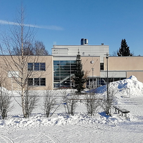 Talvinen ja luminen kirkaan päivän kuva Norssin pihasta, jossa näkyy taustalla vaalea kaksikerroksinen koulun H-siipi.