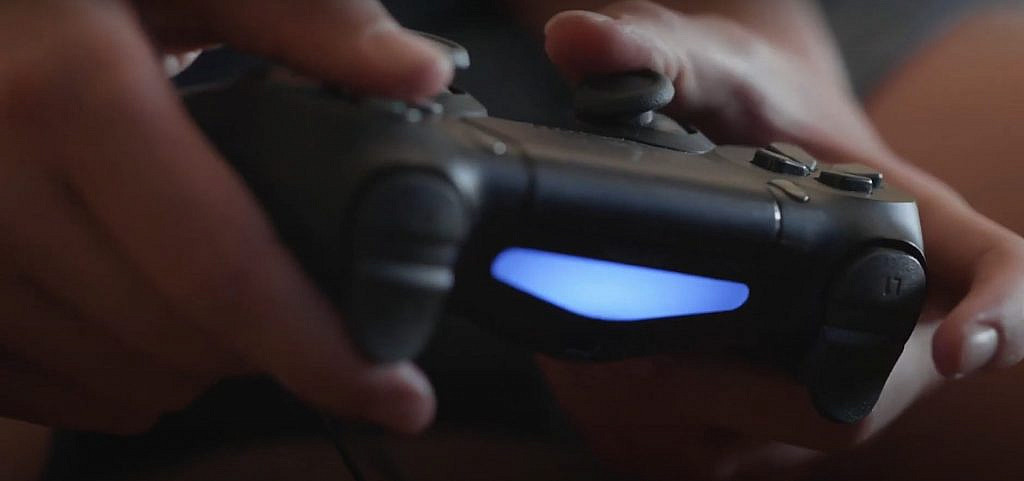 PlayStation 4-ohjain pelaajan käsissä.