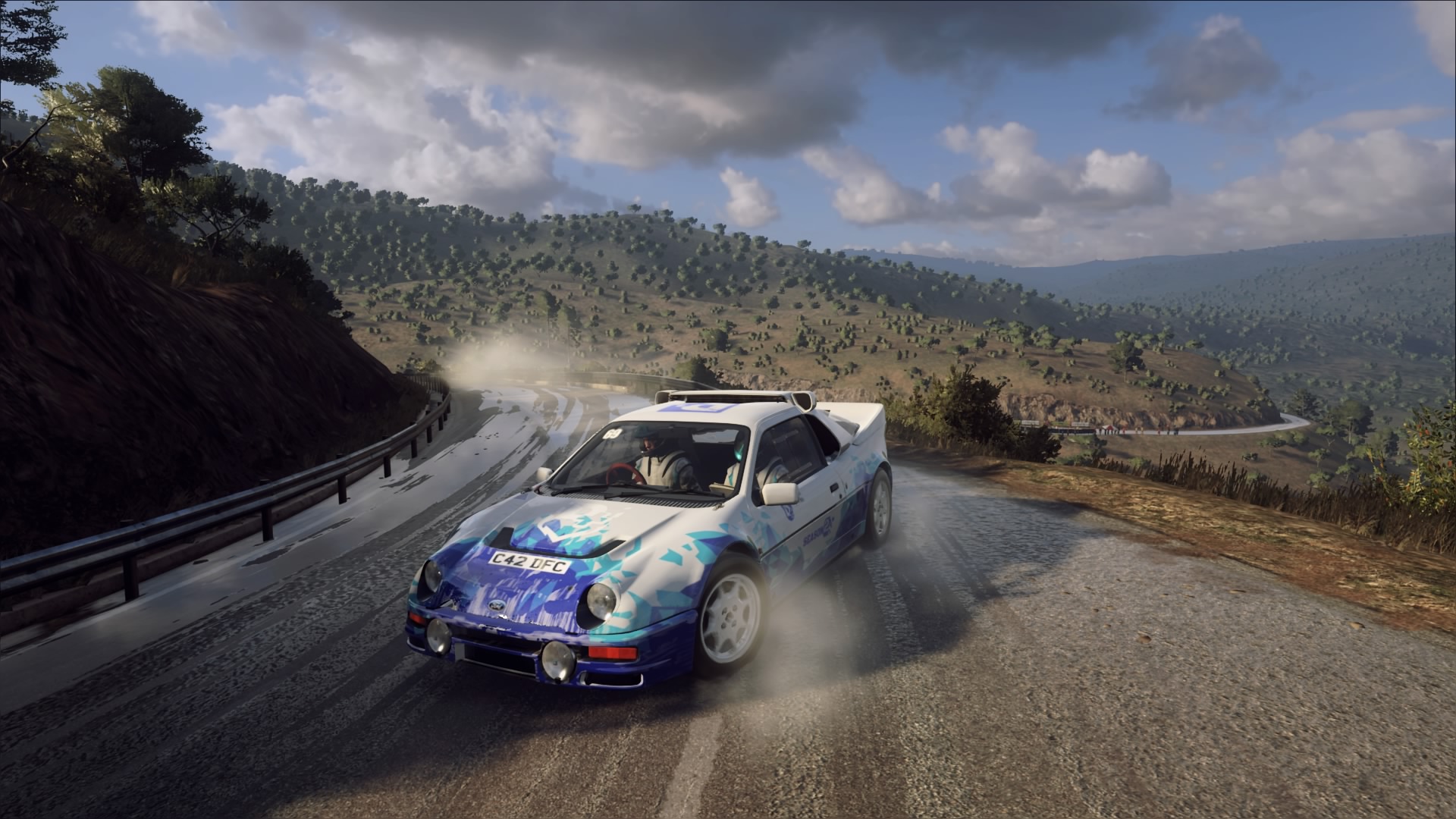 Rally car driving on pavement. Wheels are smoking while the car is turning on a tight turn.