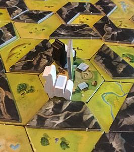 Two wooden llama chips on a game board, one white, one black. Both have a white wooden block on their back.