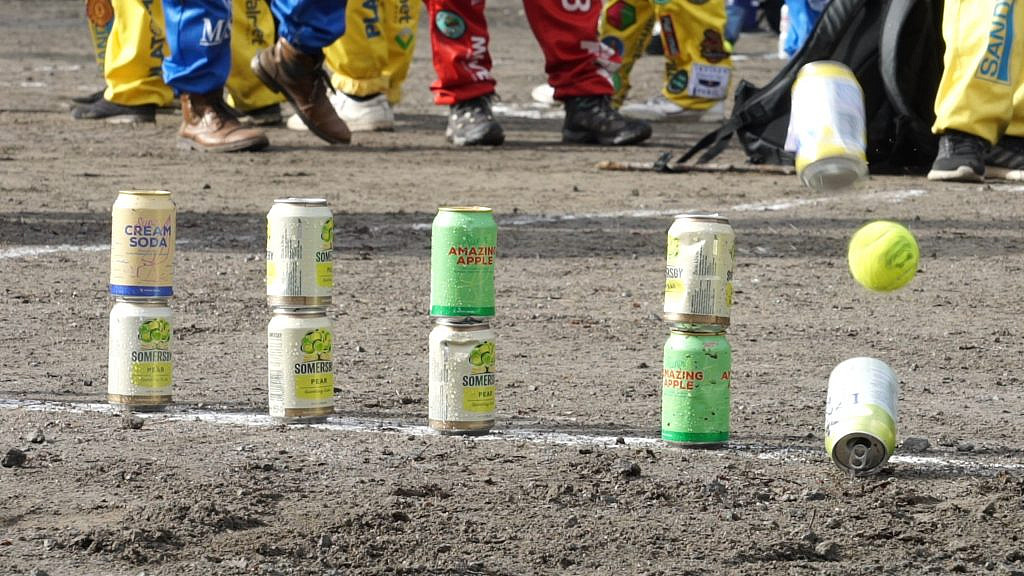 A tennis ball knocks over some cans during the game