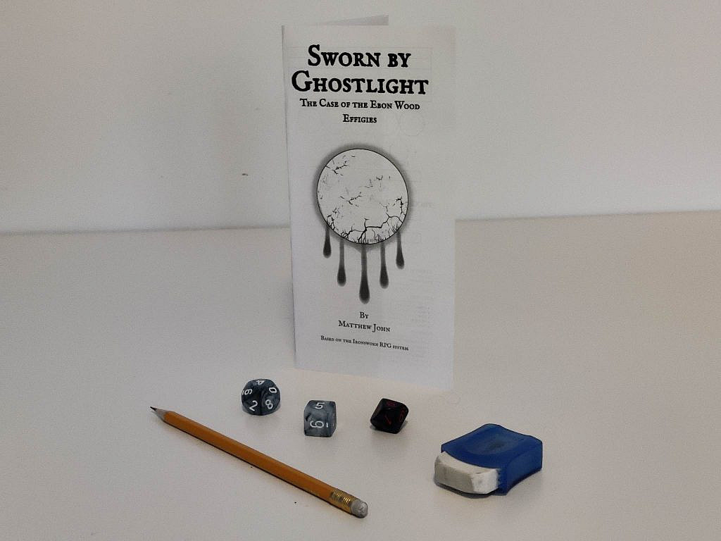 Game pamphlet, pen, eraser and three dice are on display on the table.