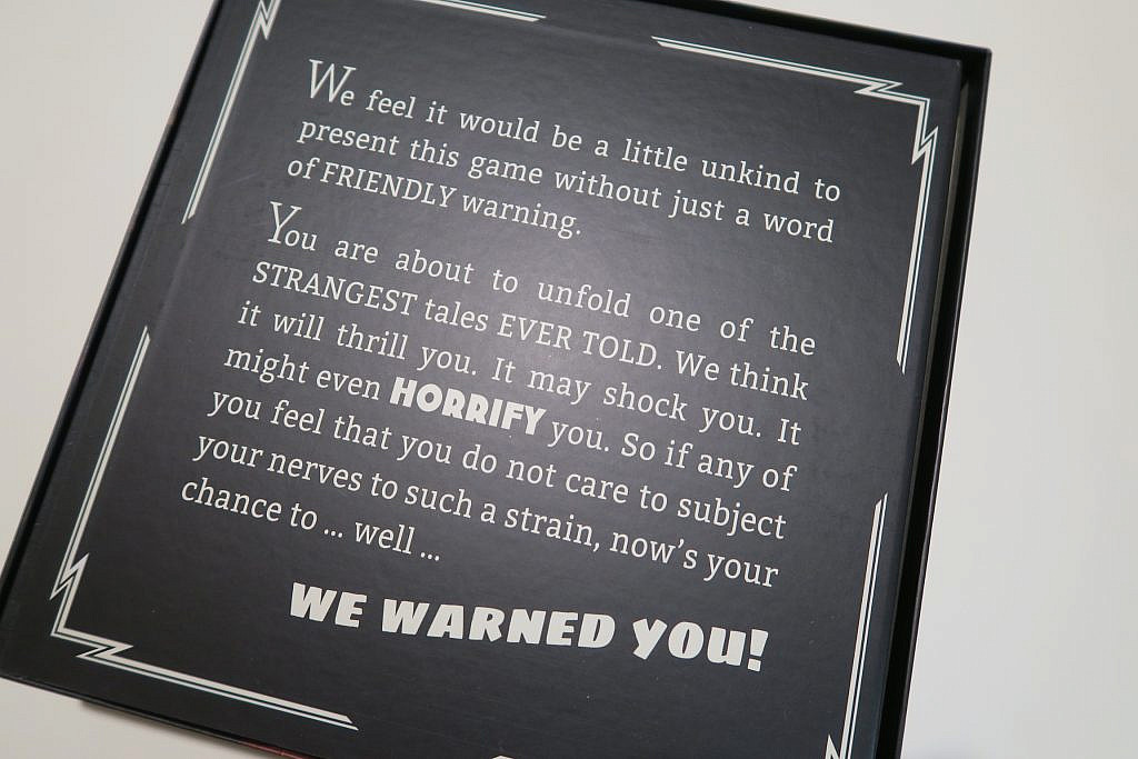 Game box opened. Shows the bottom of the board with a text: "We feel it would be a little unkind to present this game without just a word of FRIENDLY warning." written on it.