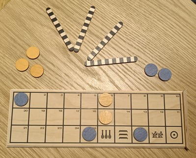 An ongoing match of Senet. One player has two pawns on board, the other player has.