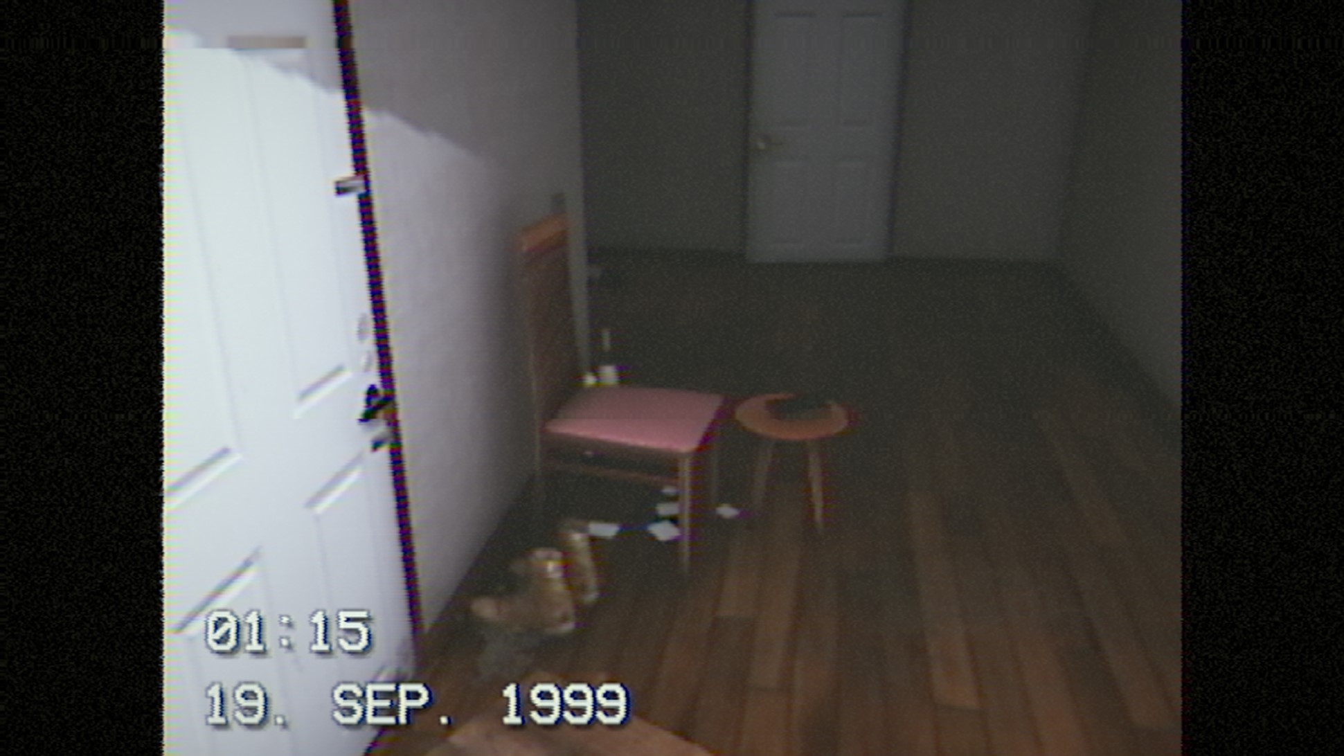 An empty-looking hallway of a detached house captured through the lens of an old camera, with the date and time displayed in the left corner. 