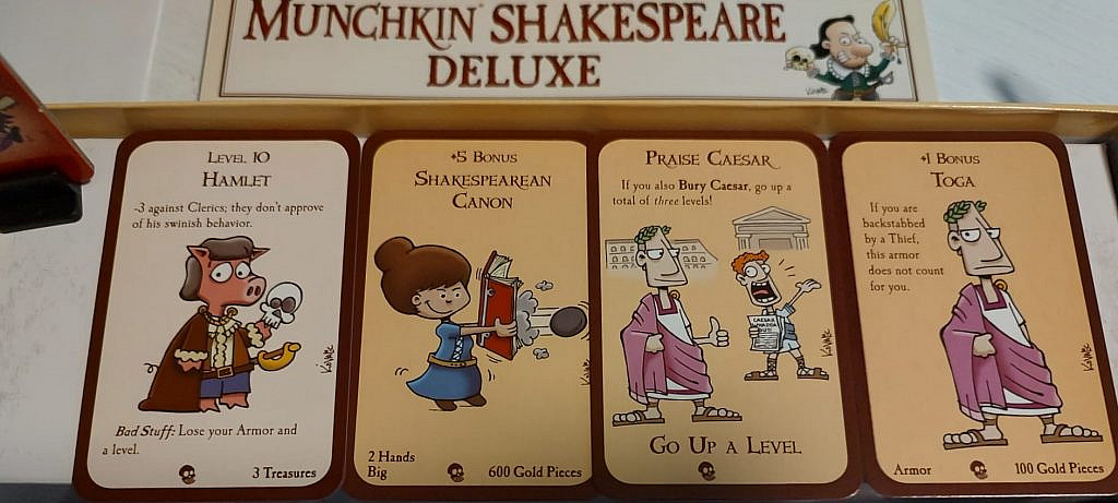 card art with a pig character dressed noble called "Hamlet" and a Shakespearean canon, a book shooting a canonball. Items, treasures, and creatures from the cardgame.