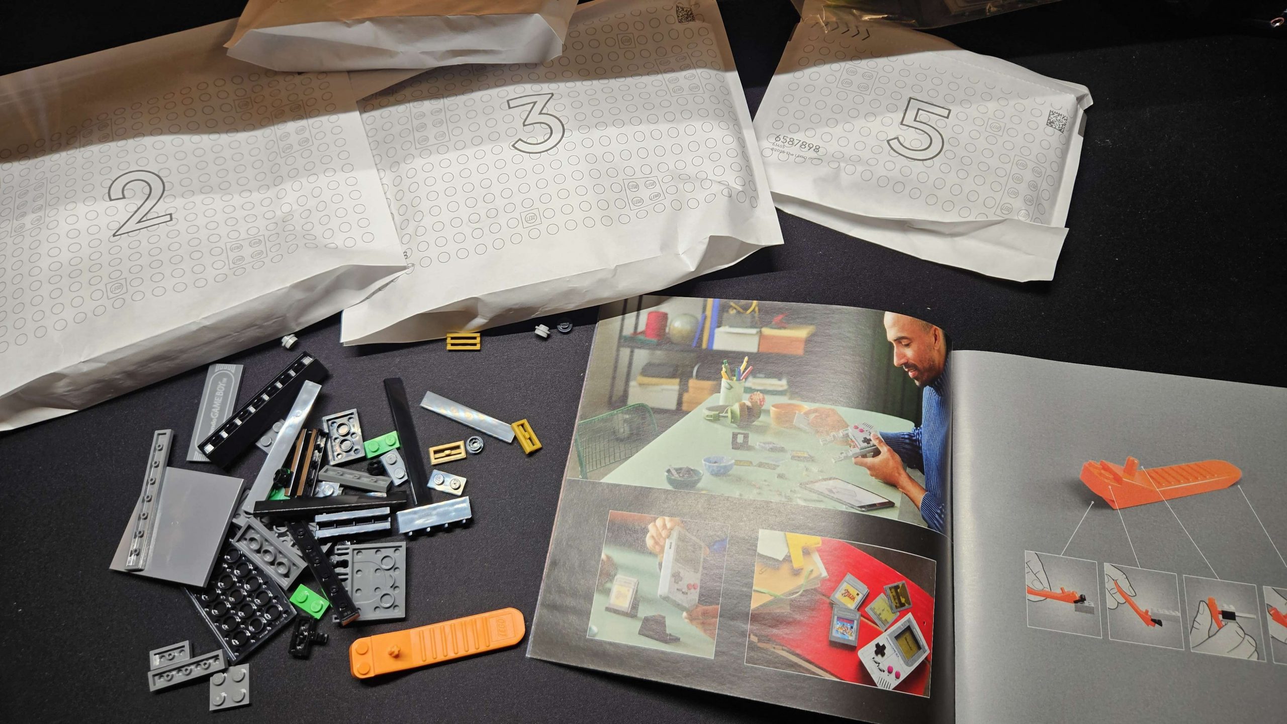 a photo of LEGO bricks scattered on a dark desk, next to instructions